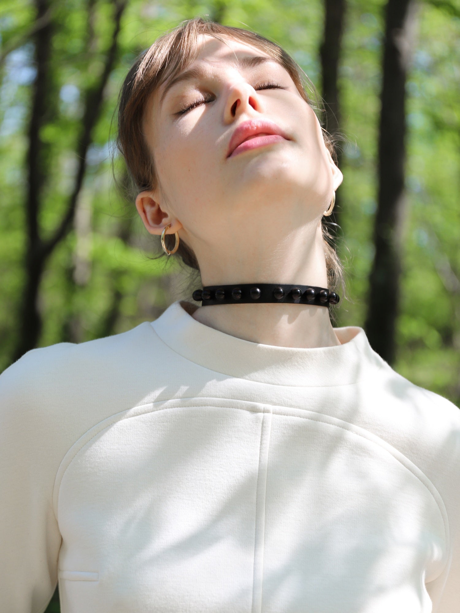 Gala in the woods wearing the Baby turns Blue Paris Billie choker with her head back