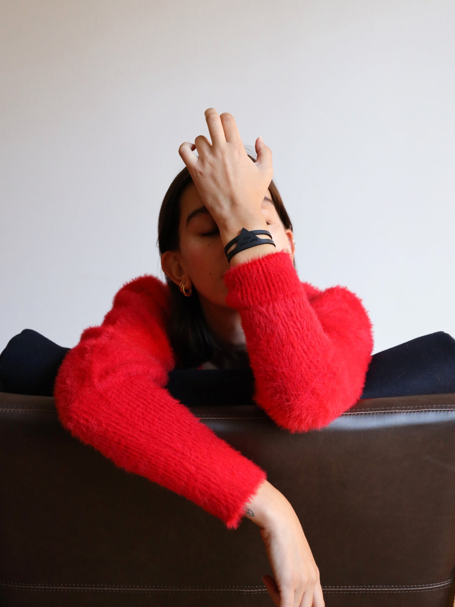 Manon sitting on a chair while wearing fiber-based Foulard cuff by Baby turns Blue Paris
