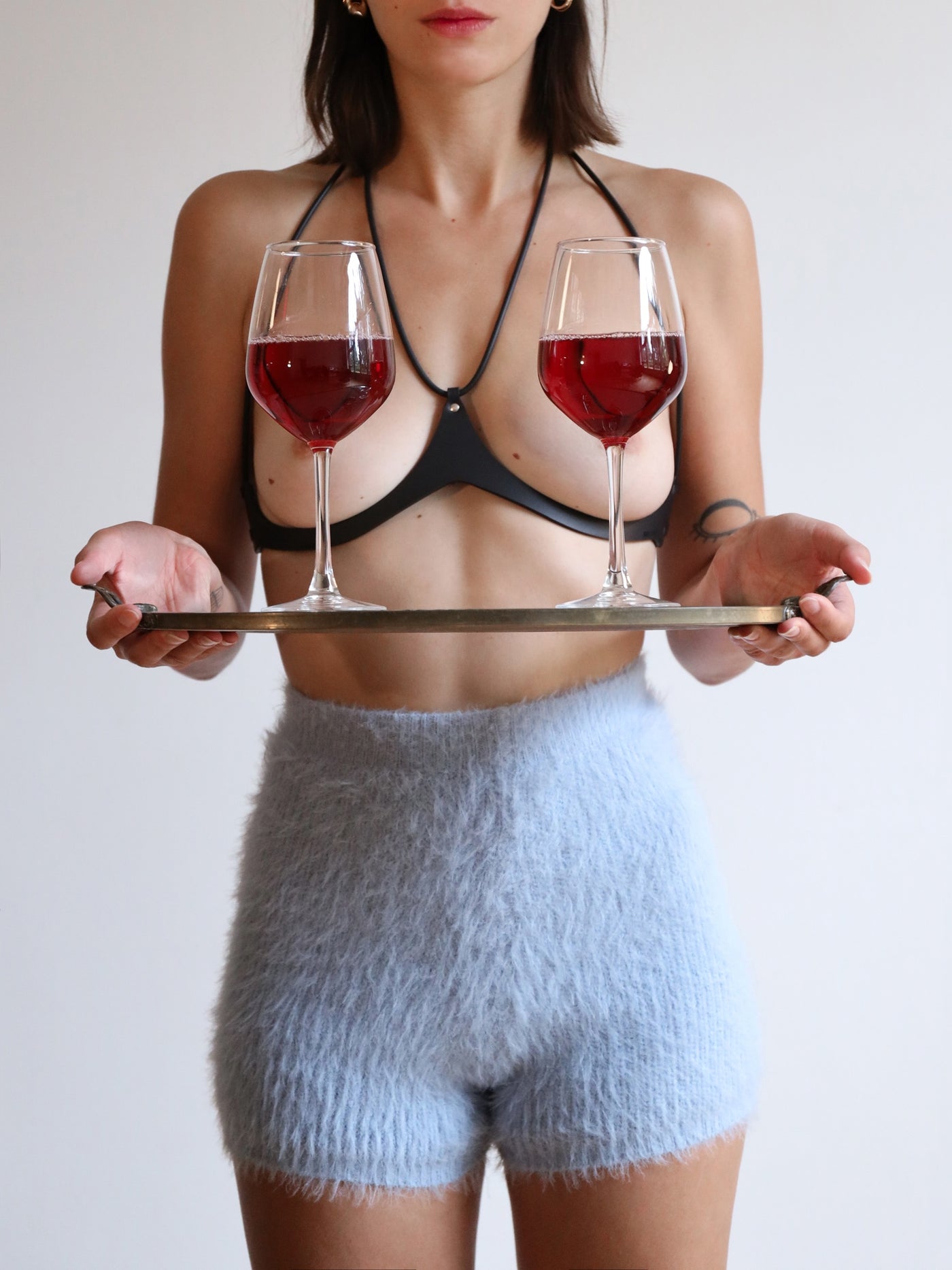 Model holding two glasses wearing the vegan Baby turns Blue Paris Candy Mini harness